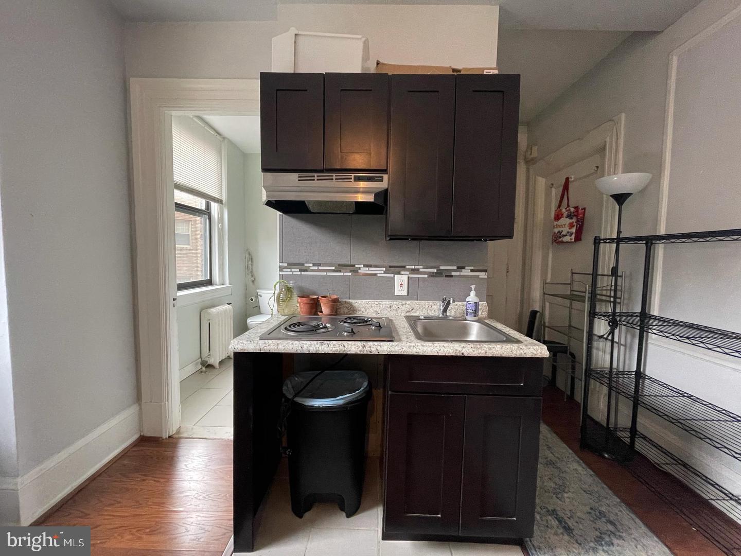 1324 Locust Street, Unit 727 Philadelphia, PA 19107 - Photo 4 of 7 a kitchen with stainless steel appliances a sink a microwave a refrigerator and wooden cabinets
