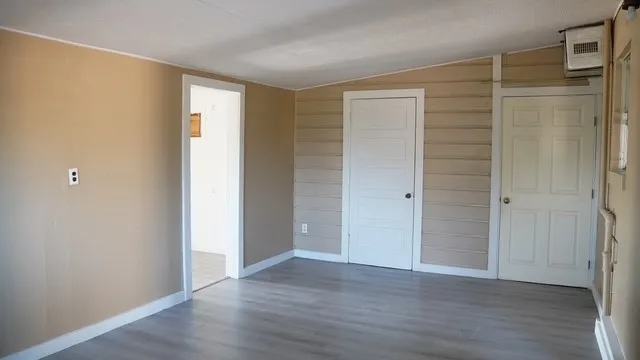 a view of an empty room with wooden floor and closet area