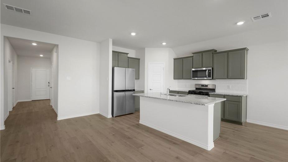 439 Epiphany Lane Lavon, TX 75166 - Photo 11 of 31 Open-concept kitchen with gray cabinetry, stainless steel appliances, white subway tile backsplash, and a central island with a granite countertop and sink