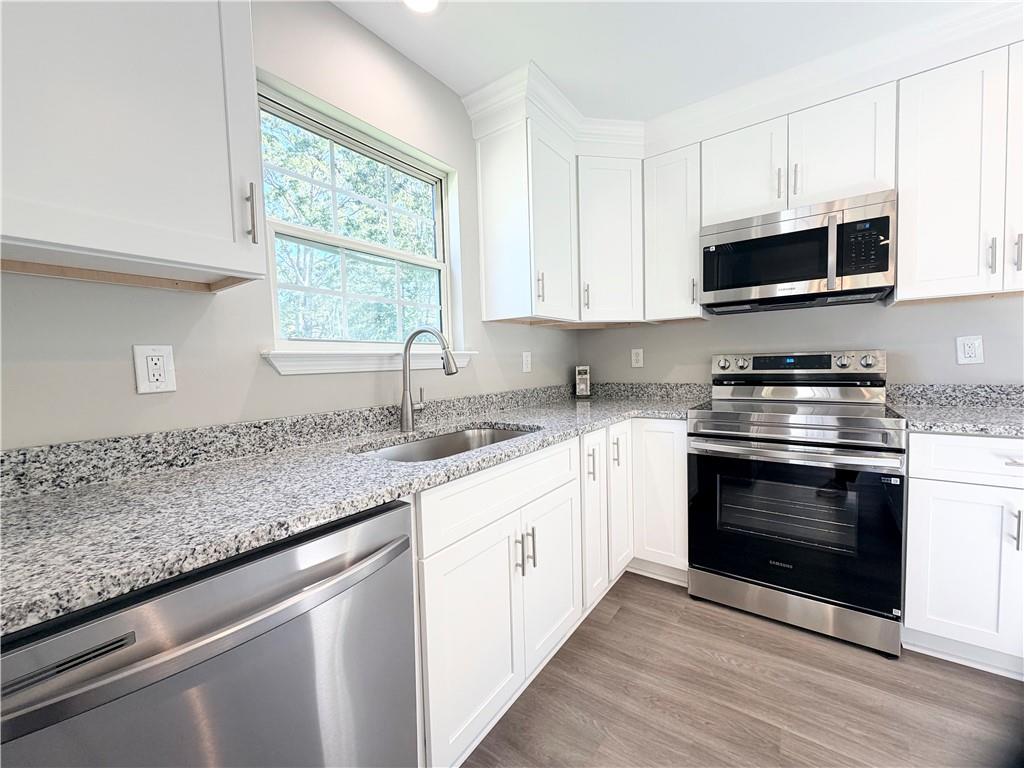 382 Arlington Lane Commerce, GA 30529 - Photo 11 of 43 a kitchen with stainless steel appliances granite countertop a sink a stove a microwave and wooden cabinets