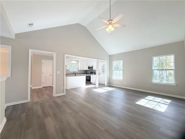a view of empty room with wooden floor and fan