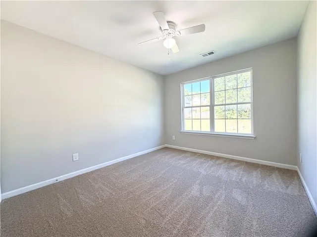 an empty room with window and ceiling fan
