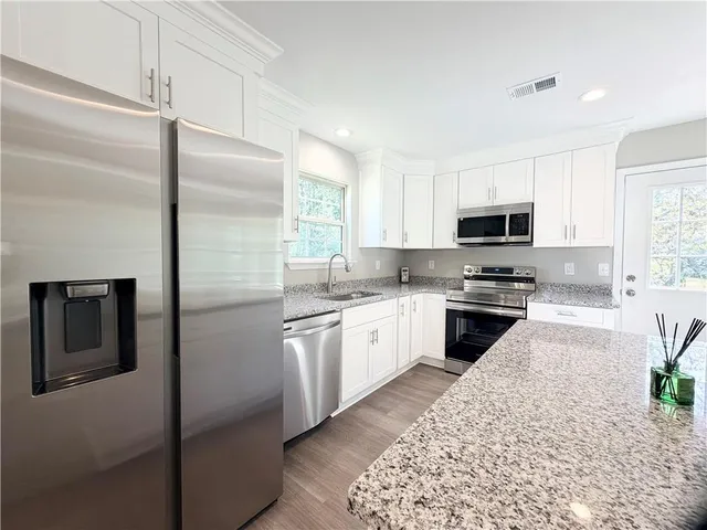 a large kitchen with a center island wooden floor and stainless steel appliances