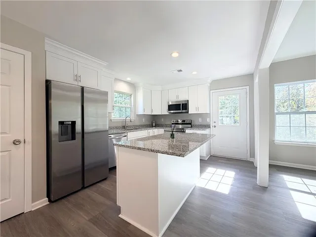 a kitchen with stainless steel appliances granite countertop a sink a stove a microwave and wooden cabinets