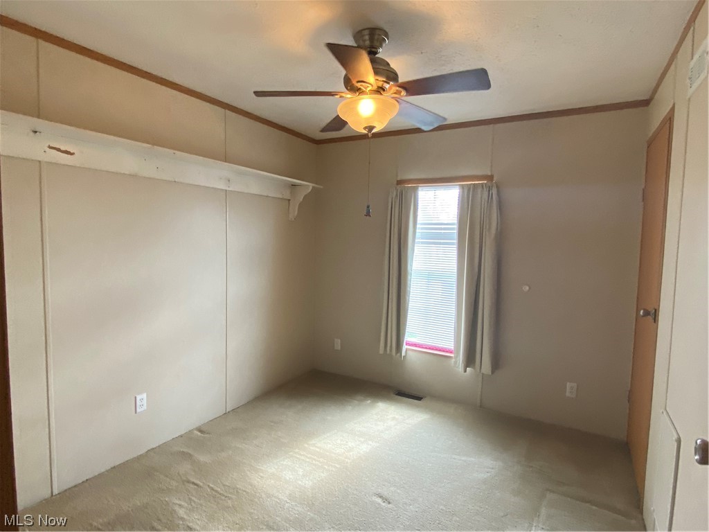 85 Rains Circle Zanesville, OH 43701 - Photo 9 of 15 Carpeted empty room featuring crown molding, plenty of natural light, and ceiling fan