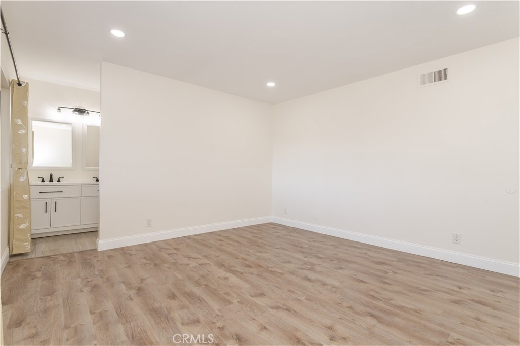 7809 Vía Udine Burbank, CA 91504 - Photo 12 of 34 an empty room with wooden floor and a kitchen