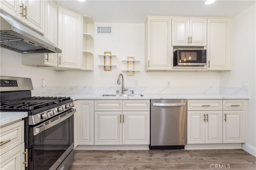 7809 Vía Udine Burbank, CA 91504 - Photo 8 of 34 a kitchen with granite countertop white cabinets and stainless steel appliances