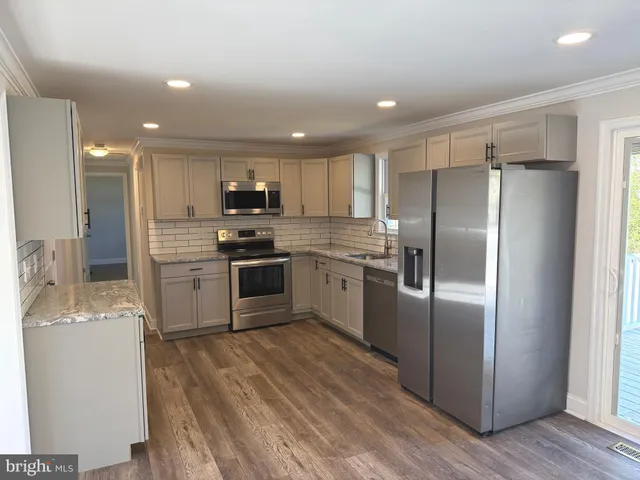 a kitchen with kitchen island a refrigerator sink and wooden floor