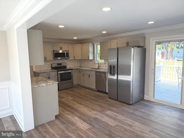 a kitchen with stainless steel appliances granite countertop a refrigerator a stove top oven a sink and dishwasher with wooden floor