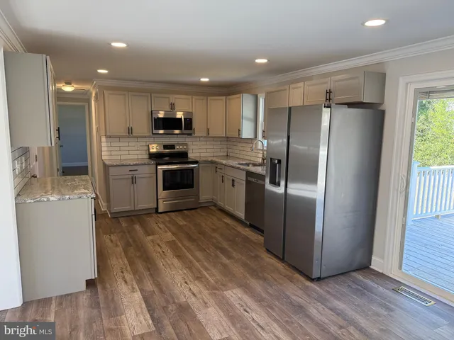 a kitchen with kitchen island wooden floors appliances and cabinets