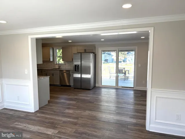 a view of a living room with wooden floor and a kitchen