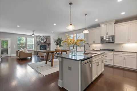 a kitchen with stainless steel appliances granite countertop a sink a stove and a wooden floors