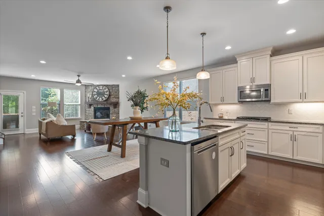 a kitchen with stainless steel appliances granite countertop a sink a stove and a wooden floors