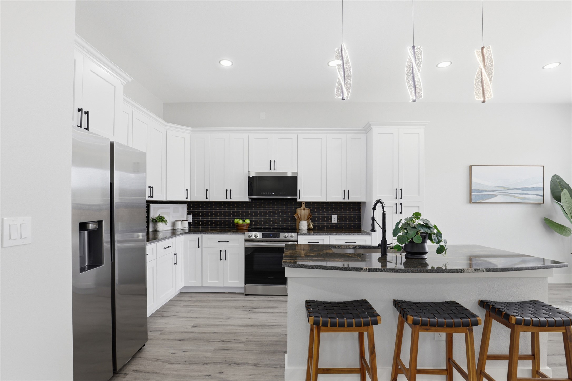 123 Los Robles Road Elgin, TX 78621 - Photo 6 of 21 Modern kitchen featuring white cabinetry with black hardware, stainless steel appliances, dark tile backsplash, and a large island with a stone countertop