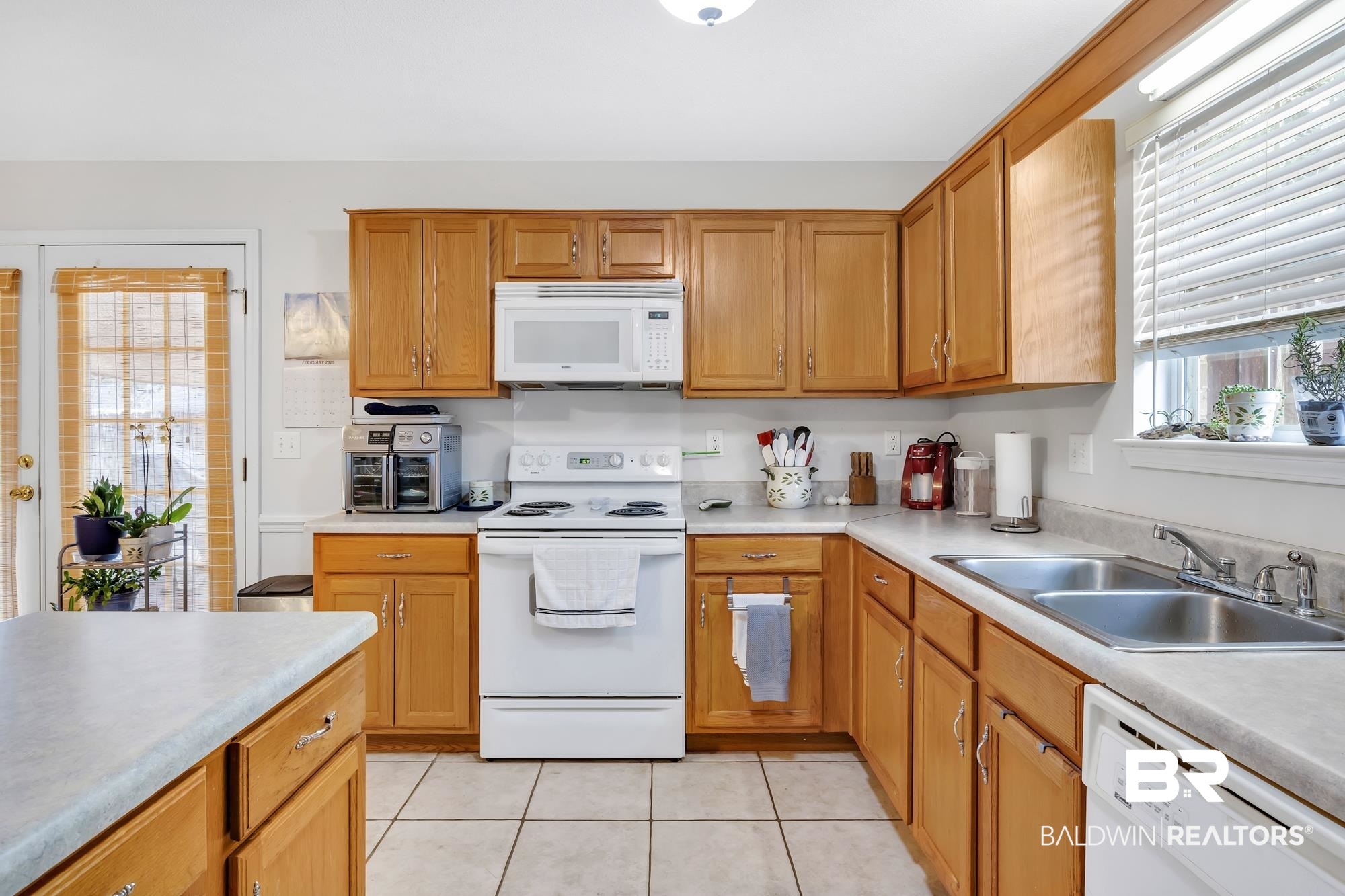105 Cluster Oaks Court Foley, AL 36535 - Photo 17 of 26 Kitchen featuring white appliances, light countertops, light tile patterned flooring, and brown cabinetry