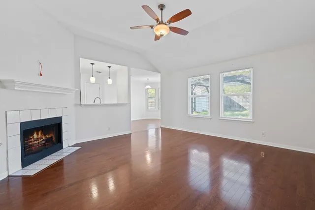 a view of an empty room with wooden floor fireplace and a window