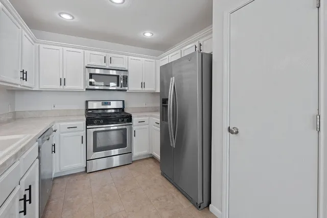 a kitchen with stainless steel appliances white cabinets and a refrigerator