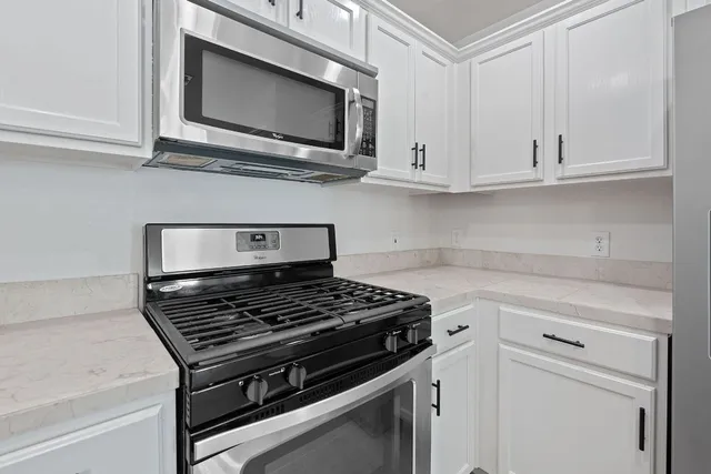 a kitchen with white cabinets and appliances