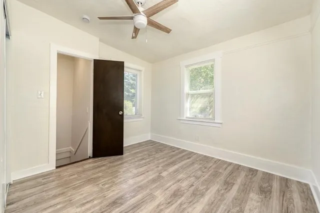 a view of an empty room with wooden floor and a window