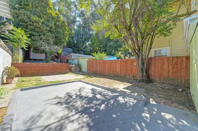 a view of a backyard with large trees and wooden fence