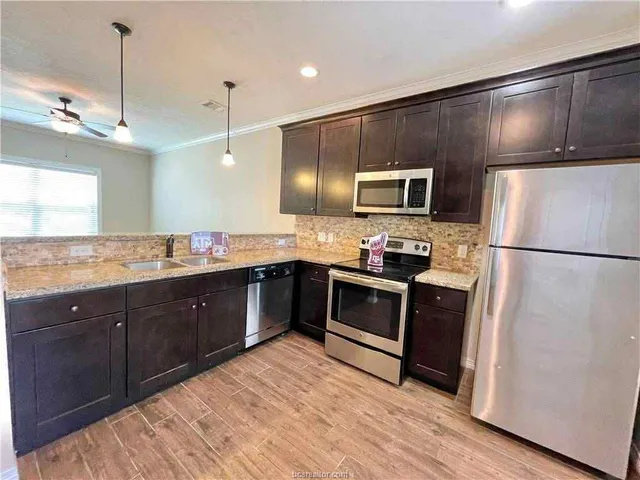 a kitchen with stainless steel appliances granite countertop a refrigerator a stove and a sink with wooden floor