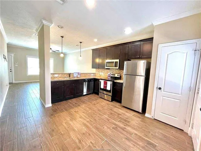 a kitchen with stainless steel appliances a refrigerator and wooden floor
