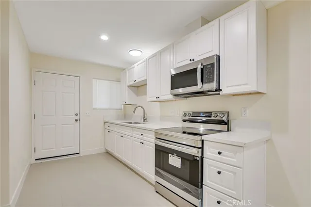 a kitchen with white cabinets and stainless steel appliances