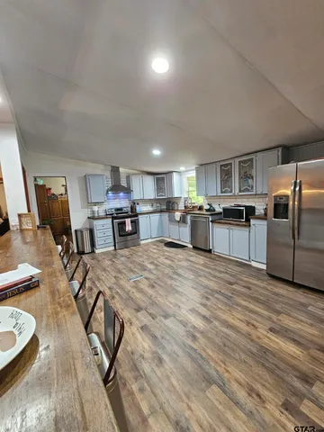 a dining room with wooden floor a chandelier a wooden table and chairs