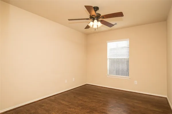 an empty room with wooden floor fan and windows
