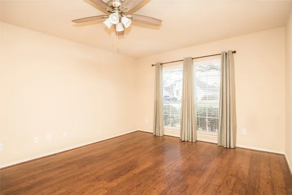 an empty room with wooden floor fan and windows