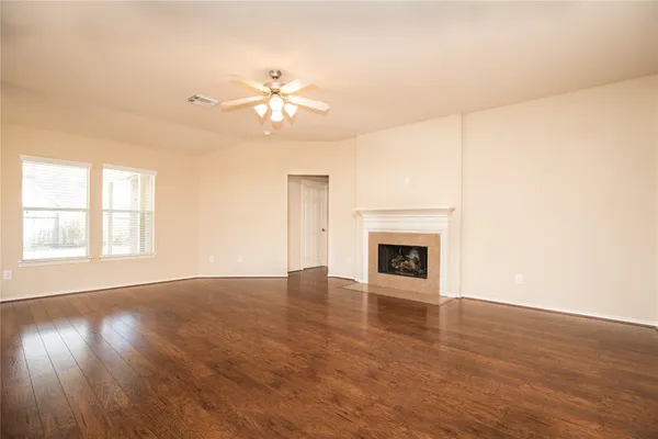 an empty room with wooden floor fan and windows
