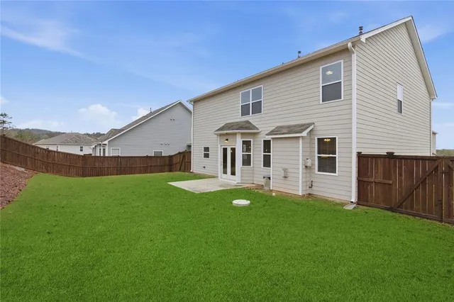 a view of a white house in front of a big yard plants and large trees