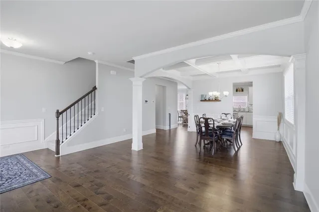 a kitchen with stainless steel appliances kitchen island granite countertop a refrigerator a stove a sink a dining table and chairs with wooden floor