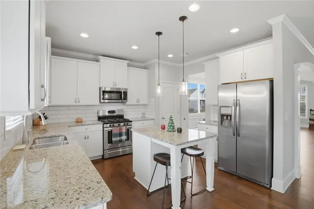 a kitchen with stainless steel appliances kitchen island granite countertop a table chairs and a refrigerator