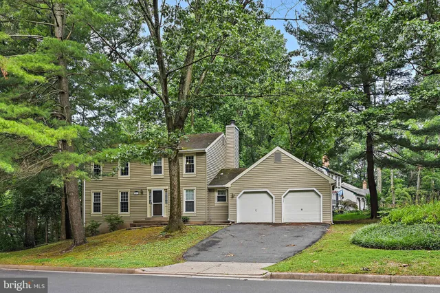 a view of house and a yard with large trees
