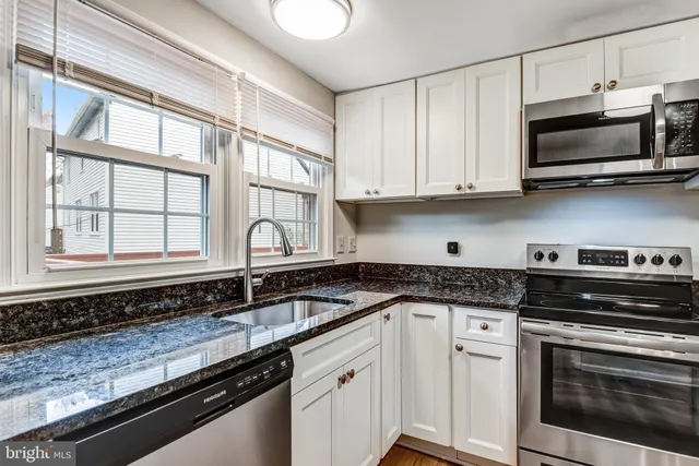 a kitchen with stainless steel appliances granite countertop a sink and a stove