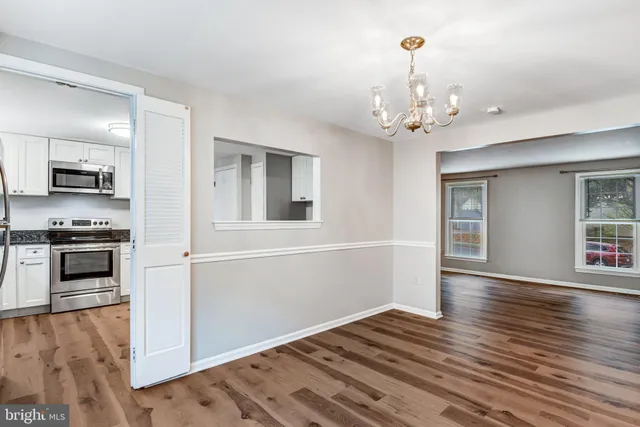 a view of a kitchen with an empty room and wooden floor