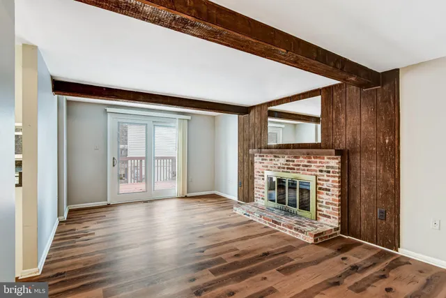 a view of an empty room with wooden floor fireplace and a window