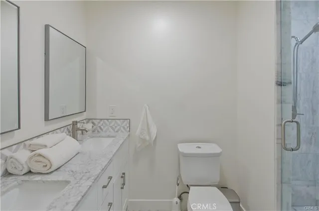 a bathroom with a granite countertop sink a toilet and mirror