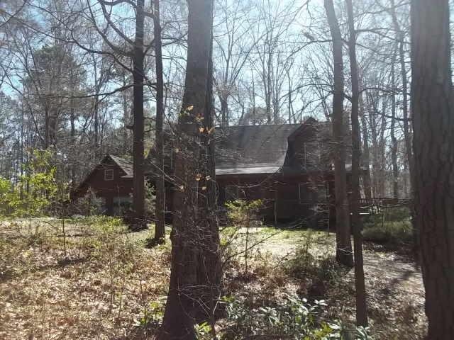 7780 Newnan Road Brooks, GA 30205 - Photo 1 of 1 a yellow house with trees in front of it