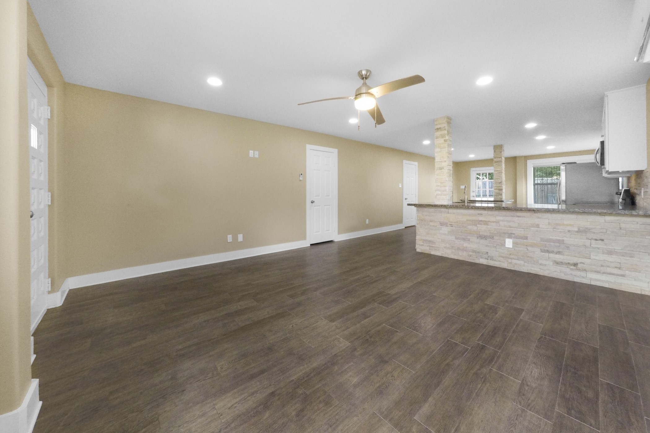 1709 Dan Street Houston, TX 77020 - Photo 9 of 29 an empty room with wooden floor a ceiling fan and kitchen view