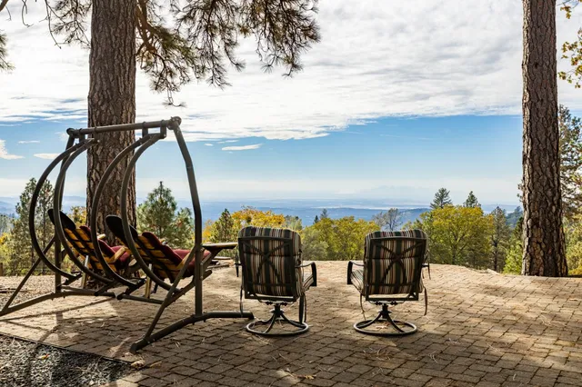 a view of a house with large trees and sitting area
