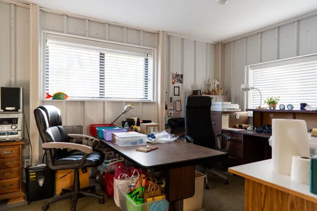 a view of a wooden house with a large tree next to a road