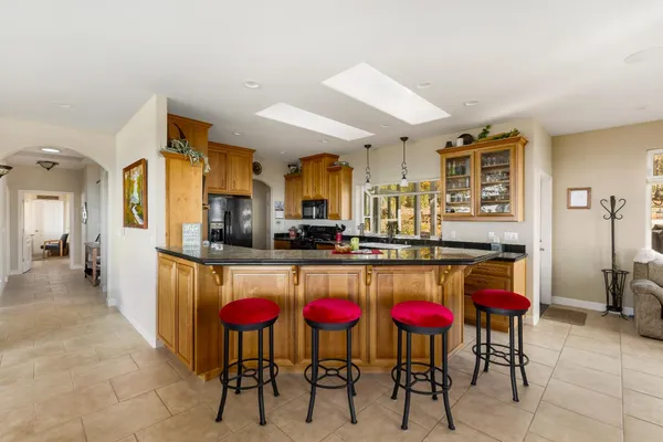 a kitchen with stainless steel appliances kitchen island granite countertop a dining table chairs and granite counter tops