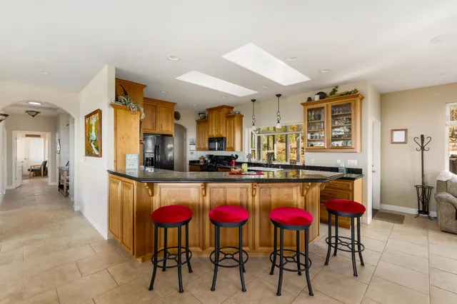 a kitchen with stainless steel appliances kitchen island granite countertop a dining table chairs and granite counter tops