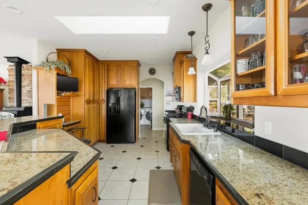 a kitchen with stainless steel appliances granite countertop a sink a stove and a wooden cabinets