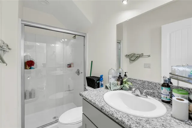 a bathroom with a granite countertop sink a toilet and shower