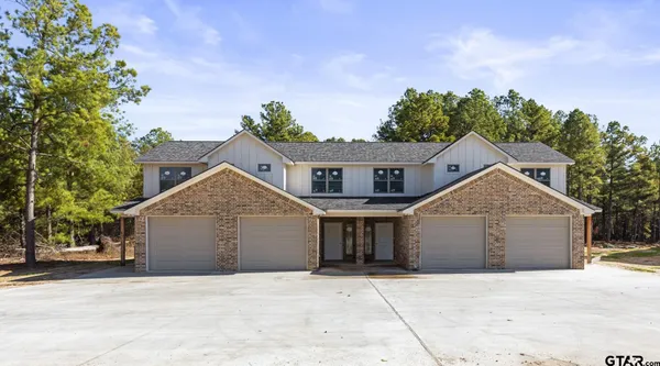 a front view of a house with a garden and trees
