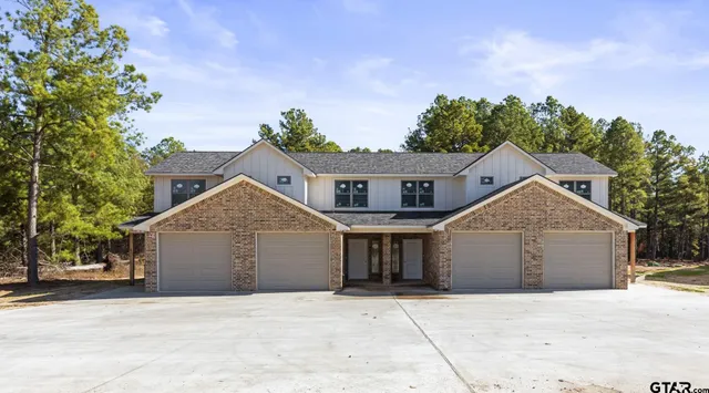 a front view of a house with a garden and trees