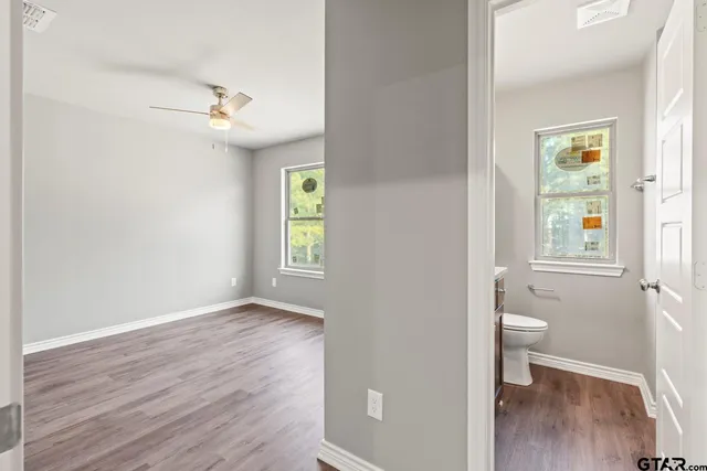 a view of an empty room with a window and wooden floor